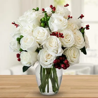 12 white roses with seasonal berries in a vase